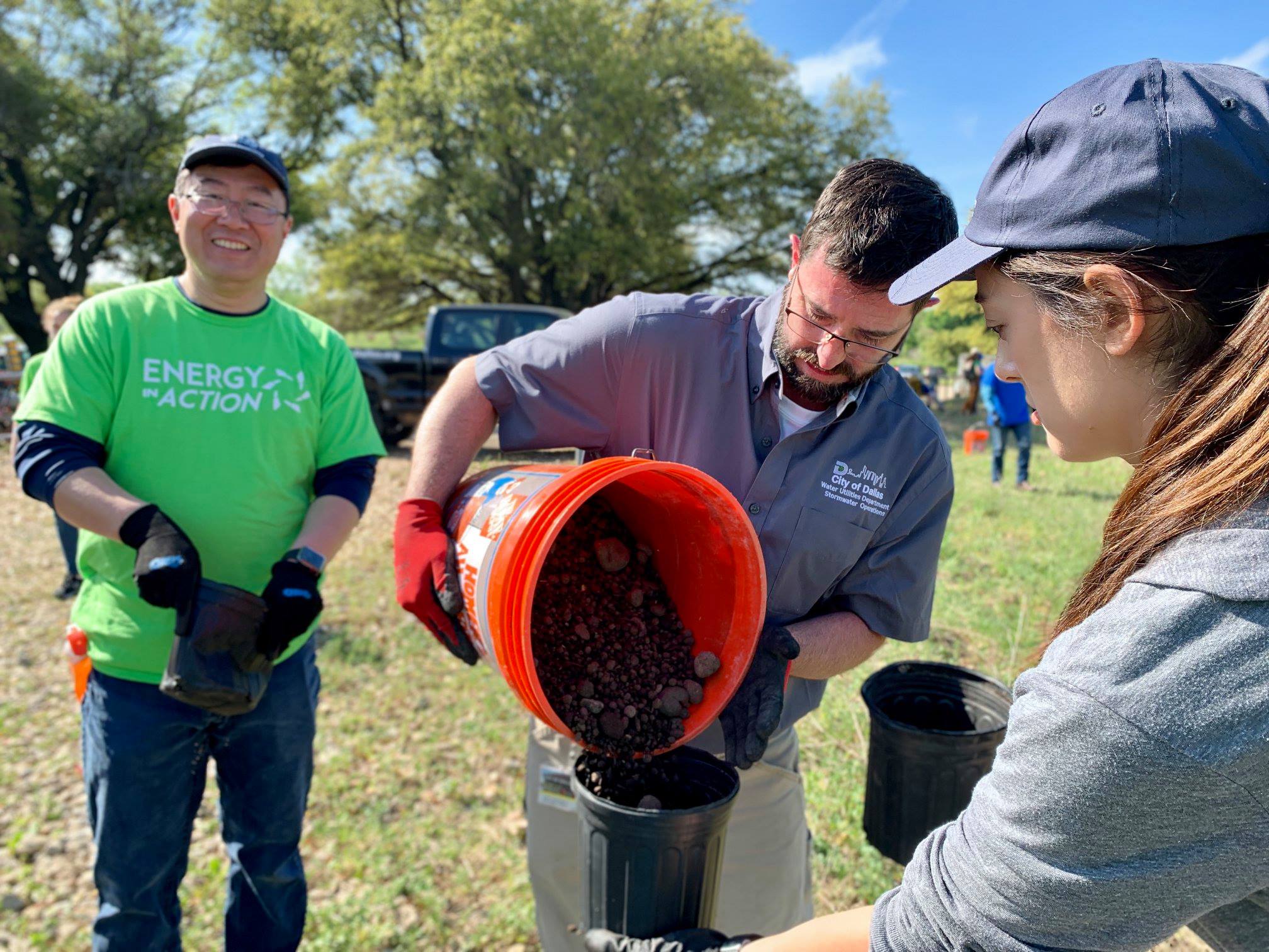 A group of people pouring dirt in buckets.