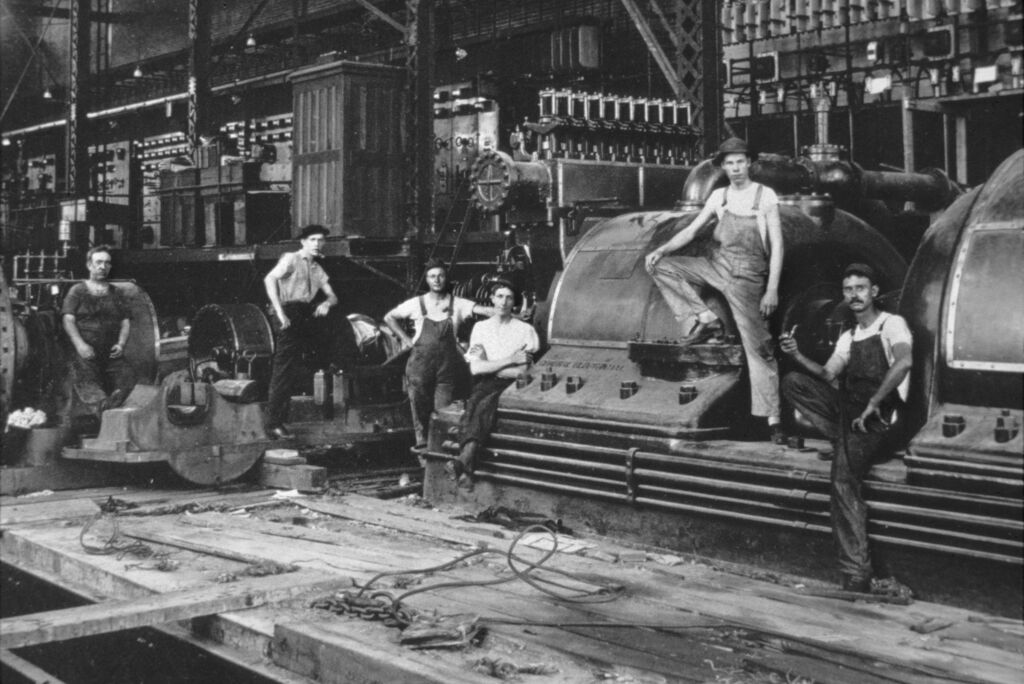 Black and white old photo men sitting on a turbine.